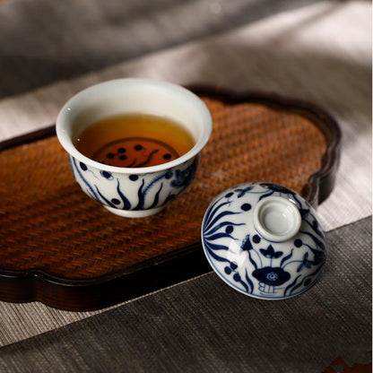 Hot water being poured into the hand-painted blue and white gaiwan filled with loose tea leaves.