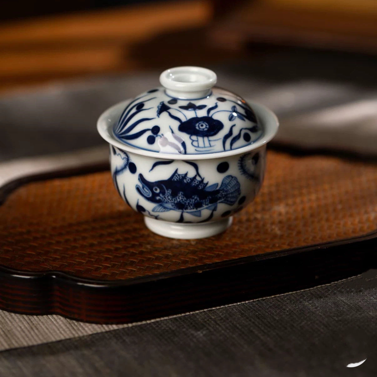 Close-up of the detailed hand-painted blue and white swimming fish motif on the porcelain gaiwan body.