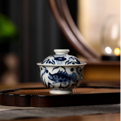 Macro view showing the vibrant cobalt blue ink tones and fine brushwork on the white porcelain gaiwan.