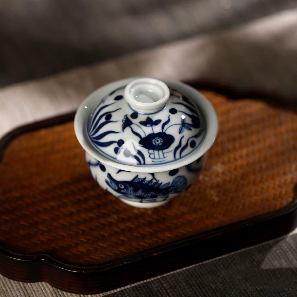 Top view of the gaiwan lid decorated with delicate hand-painted aquatic motifs and a round knob.