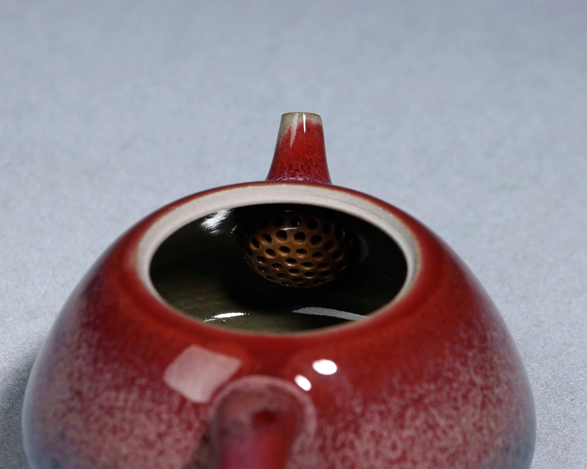 Detailed view of the straight spout and built-in filter holes inside the Jun ware teapot.