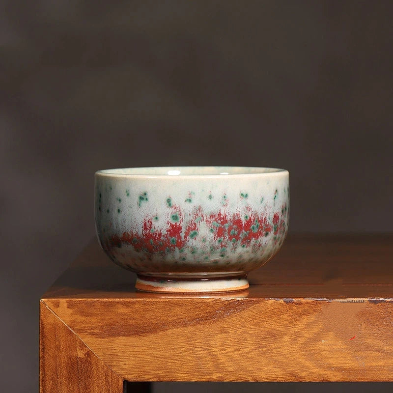 Close-up of Phoenix Tail glaze on Jun Ware teacup, showcasing unique feather-like kiln transformation.