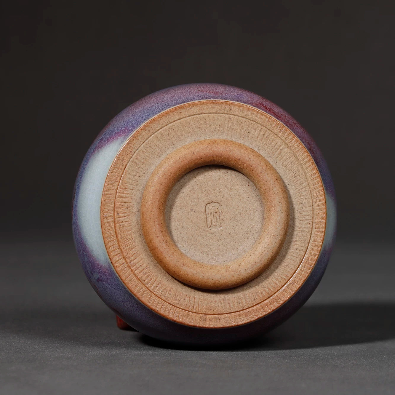 Bottom view showing the neatly trimmed unglazed foot ring and artisan hallmark of the teacup.