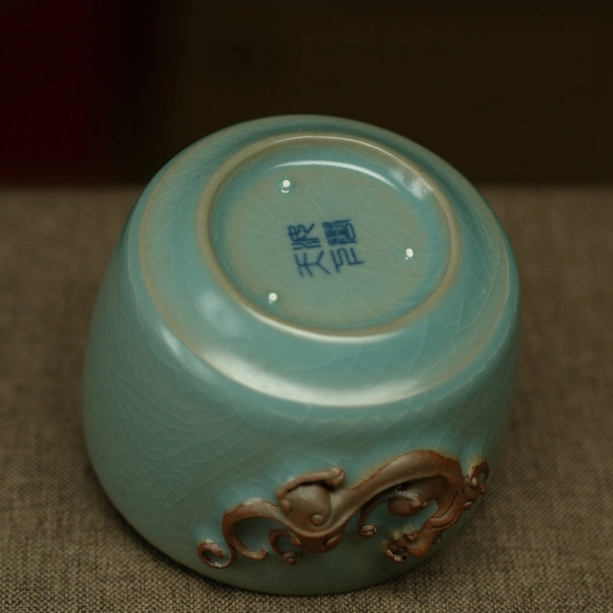 Side profile of 150ml Ru kiln sky-blue dragon relief teacup showing rounded belly and iron rim