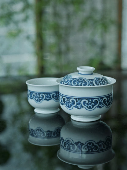 Imperial auspiciousness gaiwan set: hand-painted ruyi cloud collars, interlocking key-fret patterns, and hidden Eight Treasures in Jingdezhen blue-and-white porcelain tradition.