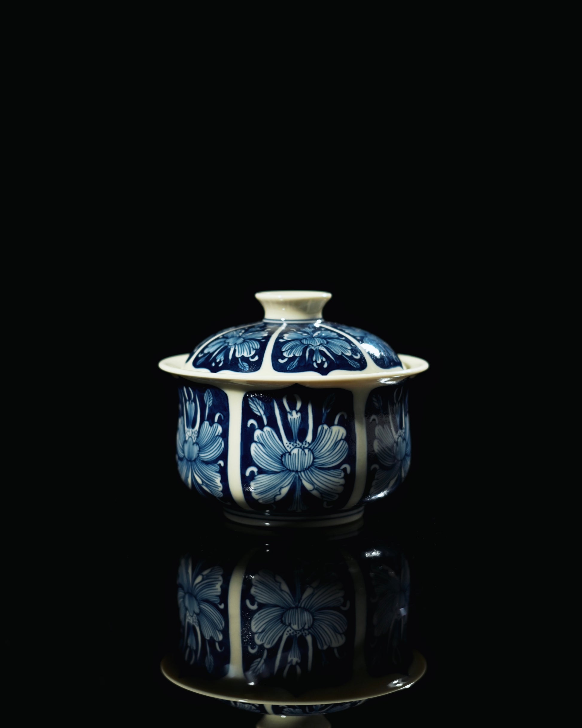 Peony motif in reserved white showing layered petals on blue porcelain surface