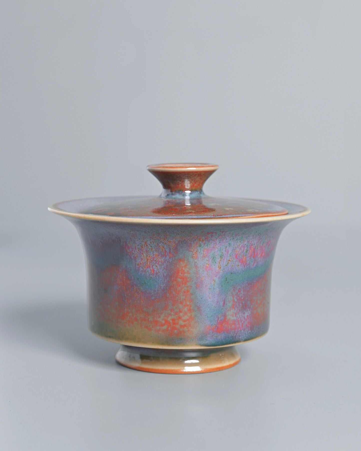 Lavender and oxblood glaze hues blending through spontaneous kiln chemistry reactions