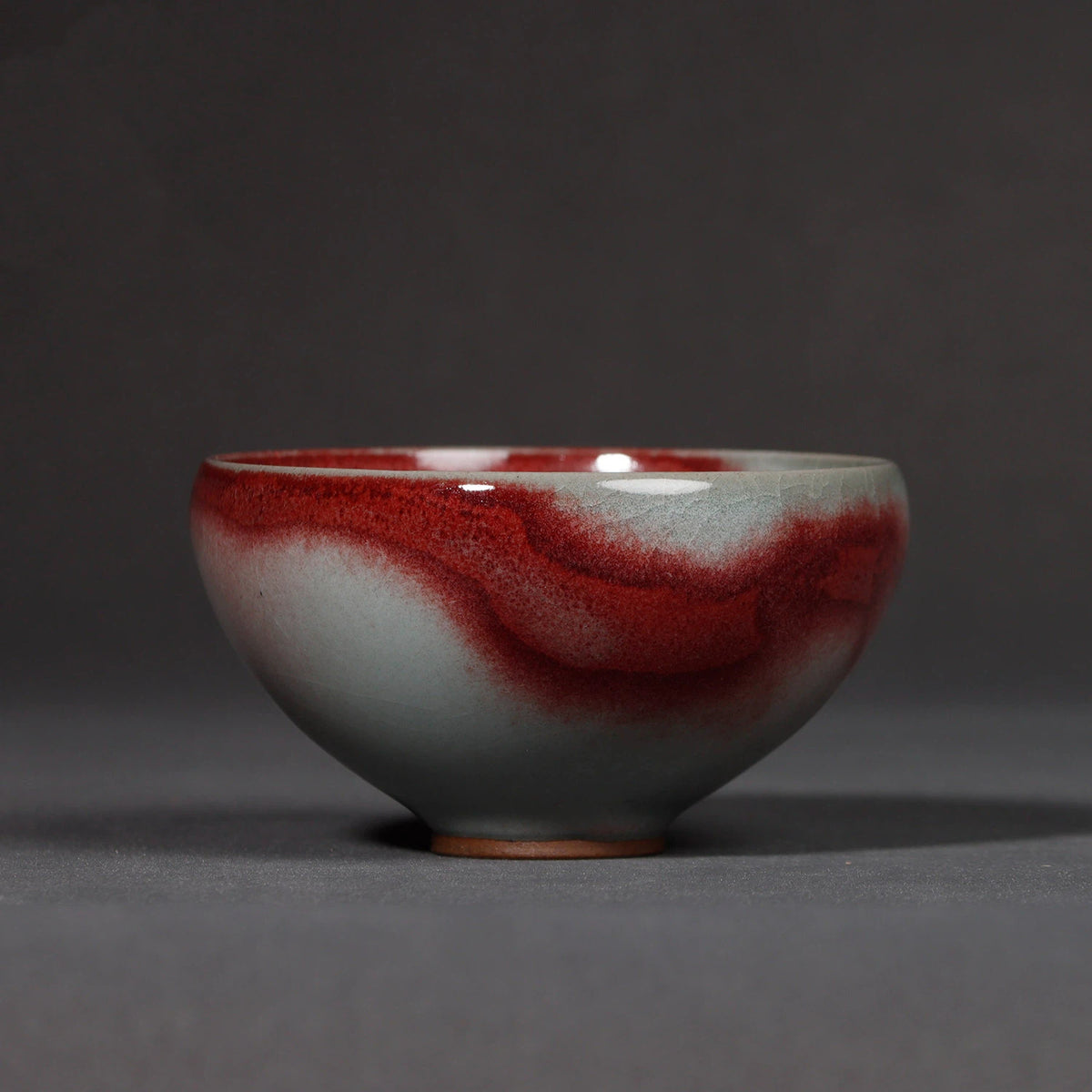 Close-up of the serene moon-white glaze contrasted with dynamic red splash kiln transmutation.