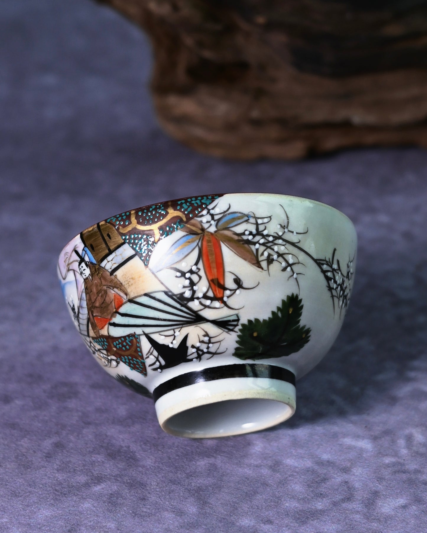 Hand-painted Ukiyo-e style figure on a Kutani tea cup, dressed in traditional kimono with bold red, gold, and black enamel colors.