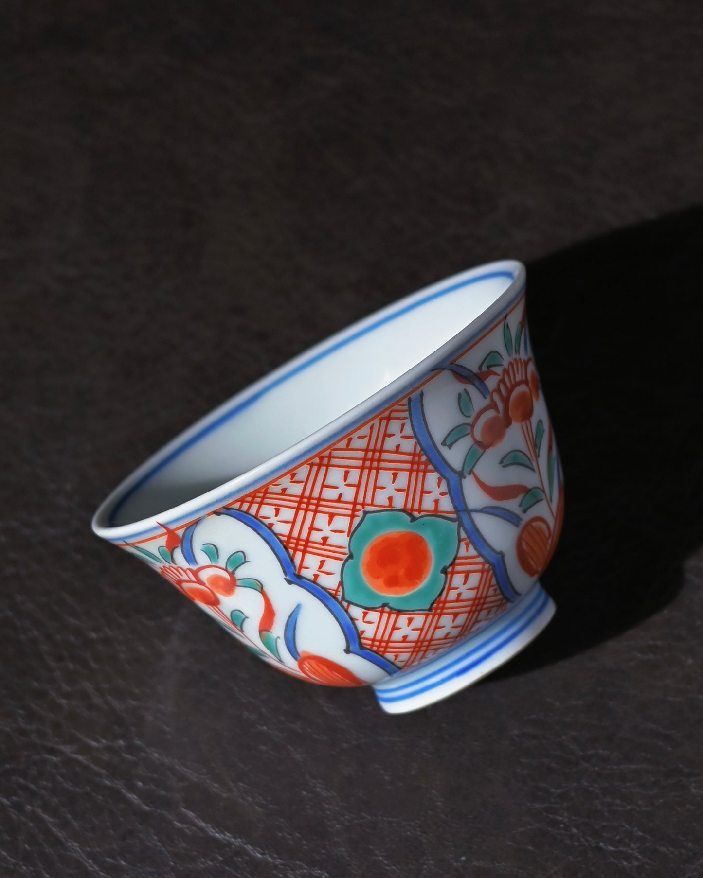 Kutani tea cup showing white plum blossoms and autumn leaves painted in delicate overglaze enamel.