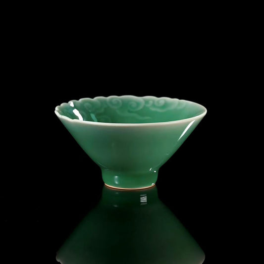 Longquan celadon teacup with plum green glaze and raised auspicious cloud patterns, handmade using traditional techniques