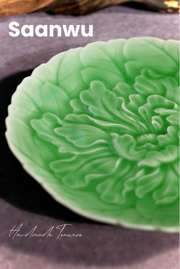 Macro view of the high-relief carved peony flower pattern on a Longquan Celadon tea saucer.
