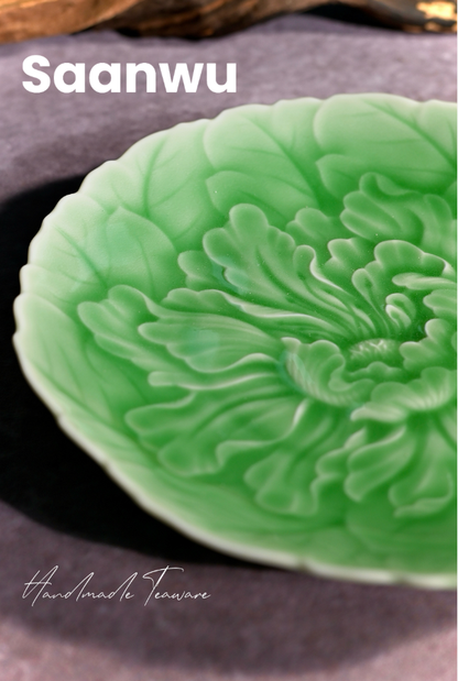 Macro view of the high-relief carved peony flower pattern on a Longquan Celadon tea saucer.