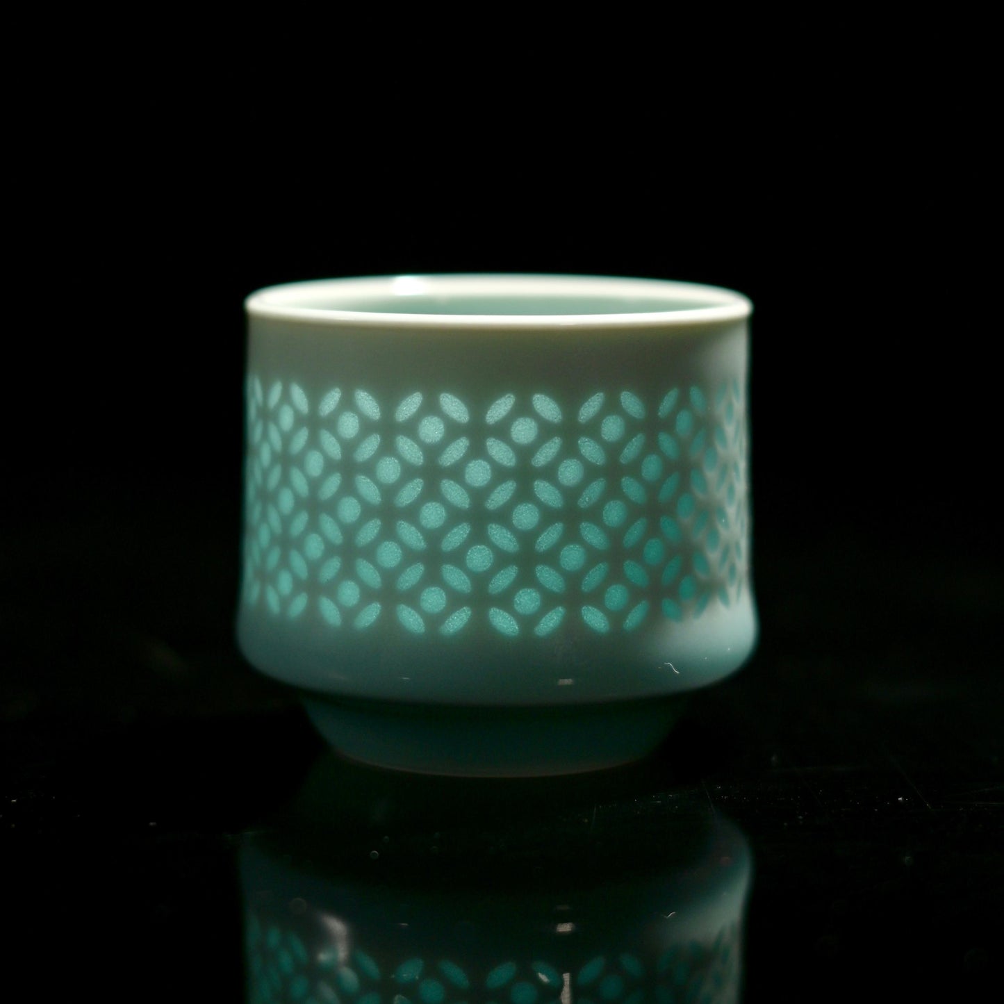 Longquan Celadon Linglong Cup front view showing translucent floral patterns under celadon glaze