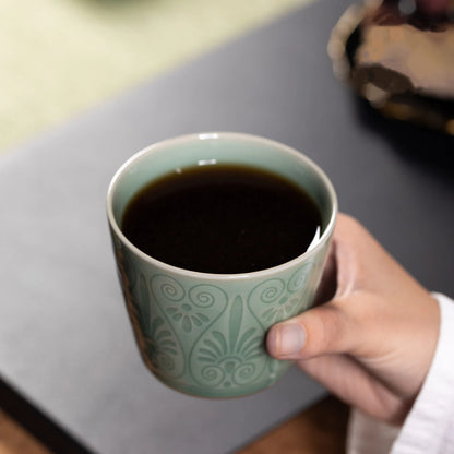 A rich espresso or poured coffee inside a Longquan Celadon Plum Green Relief Carved Cup