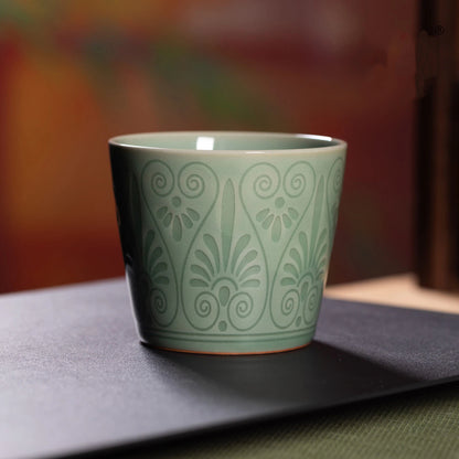 Longquan Celadon Plum Green Relief Carved Cup set on a wooden tray for versatile daily drinkware.