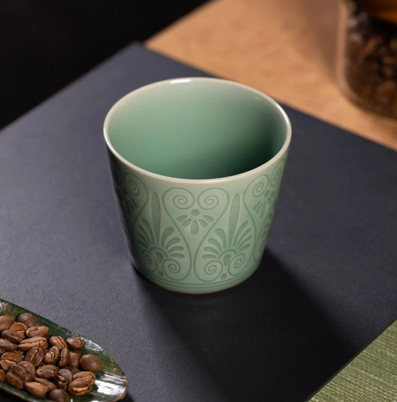 Macro view showing the deep plum green glaze pooling over the relief carved details.