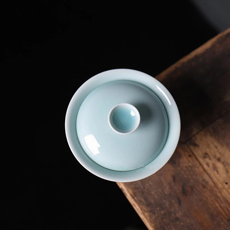 Longquan Celadon Thin Porcelain Calligraphy Gaiwan placed on a wooden tea tray with tea accessories.