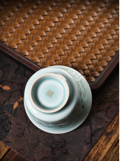 Powder-green Fenqing celadon tasting cup with glowing translucent flower lattice detail