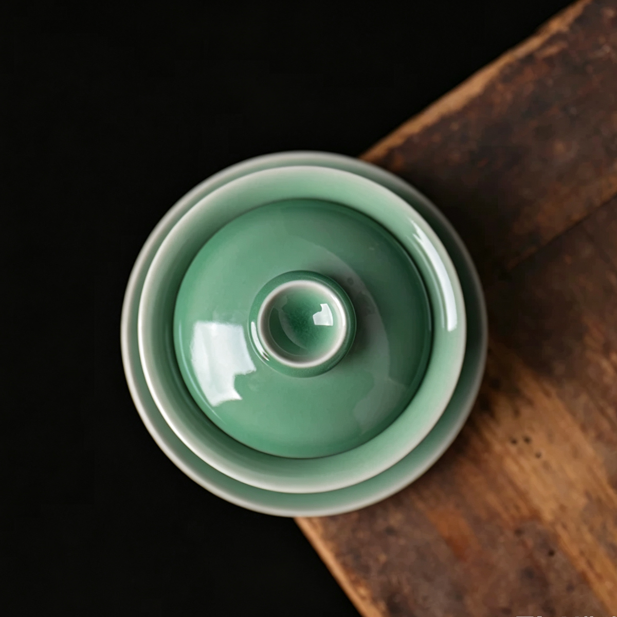 Close-up of plum green celadon gaiwan lid knob and flared rim showing crisp white accent lines