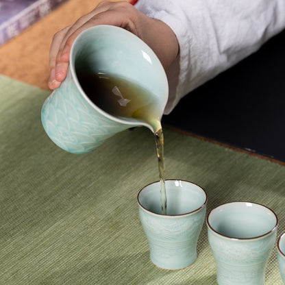 Detailed macro view of jade-green celadon glaze pooling over hand-carved dragon scales on tea pitcher