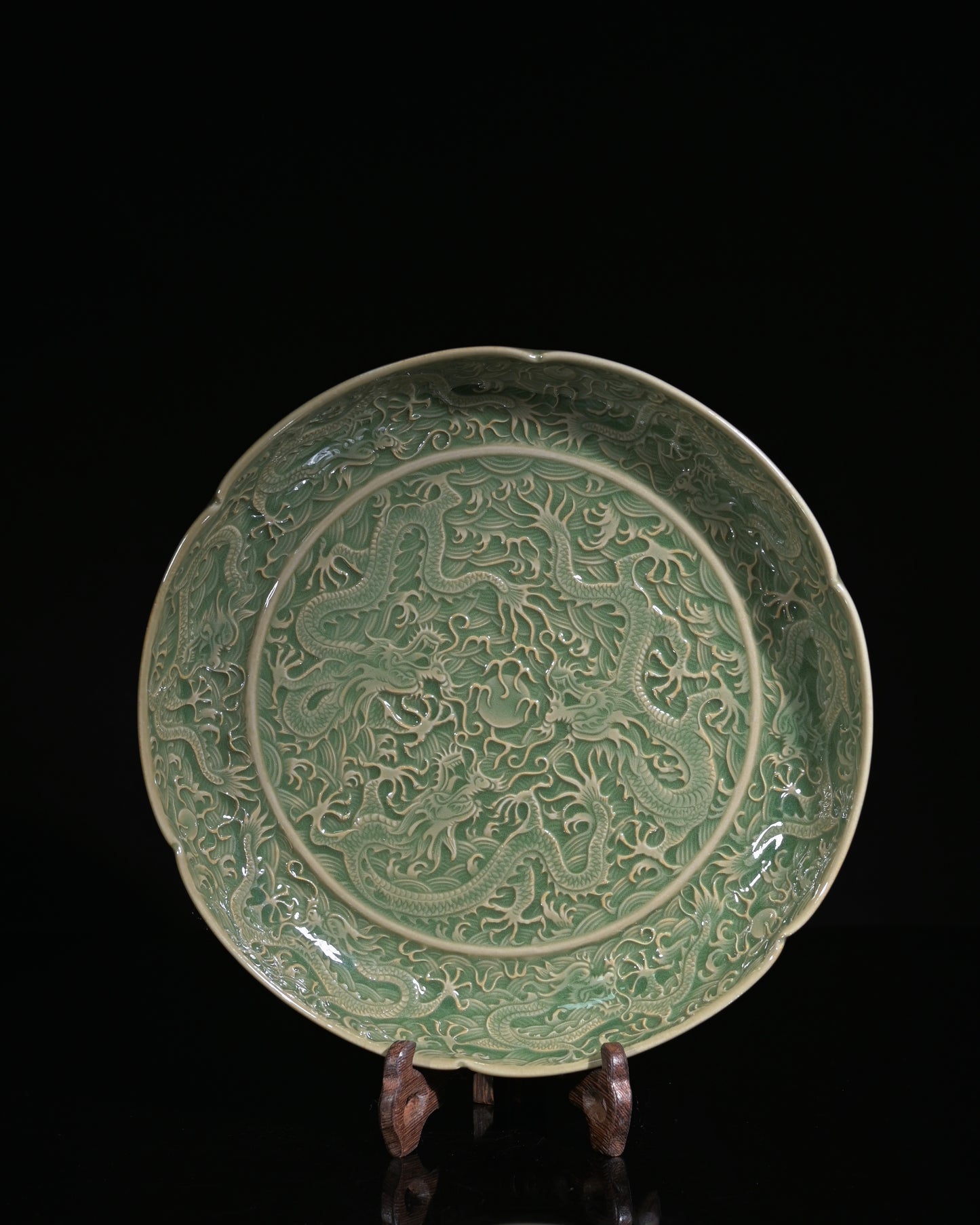 Northern Song dynasty carved celadon dish showing deep three-dimensional dragon relief under olive glaze