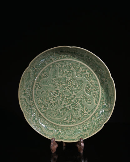 Northern Song dynasty carved celadon dish showing deep three-dimensional dragon relief under olive glaze