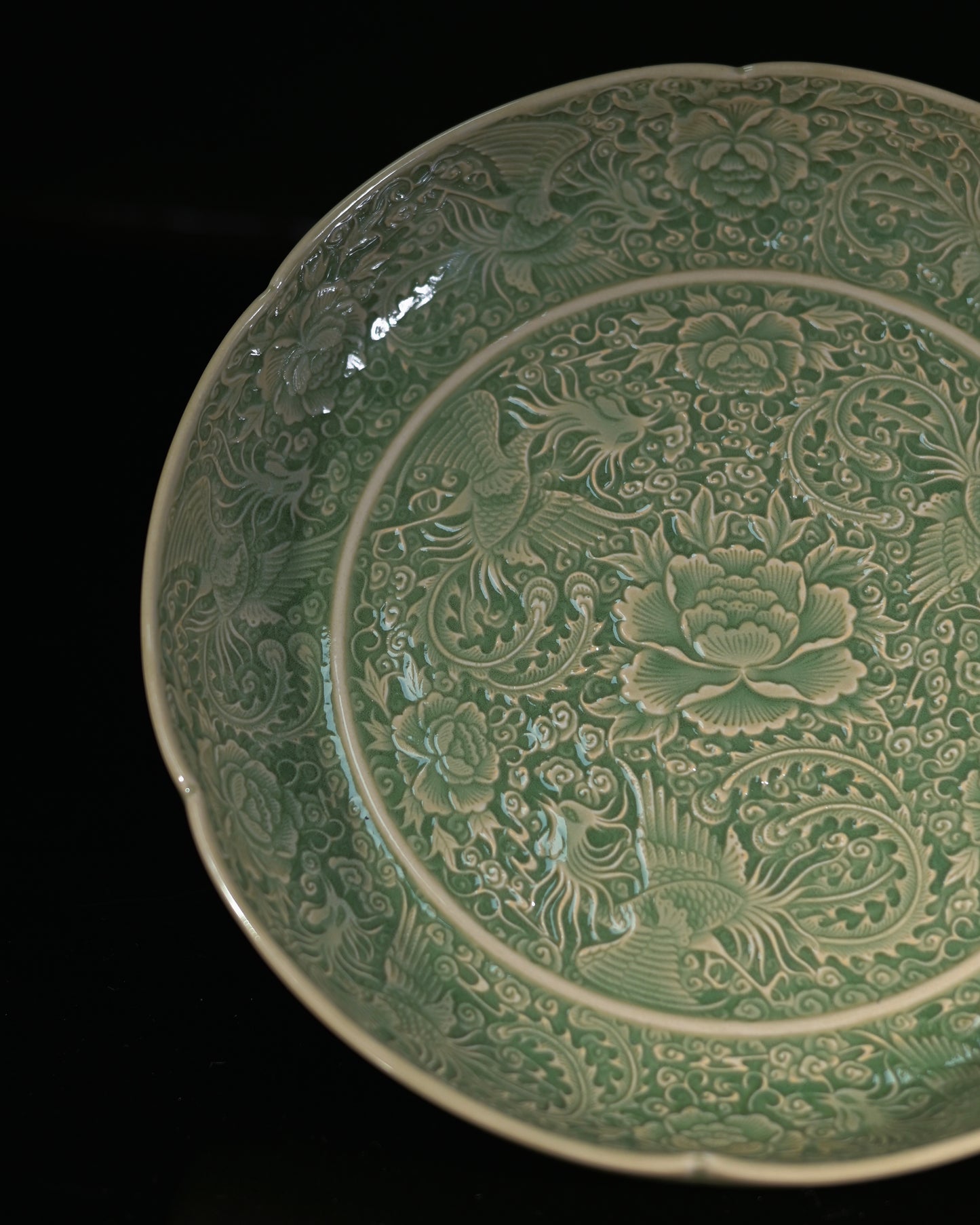Northern Song carved celadon dish showing deep three-dimensional phoenix relief under olive glaze