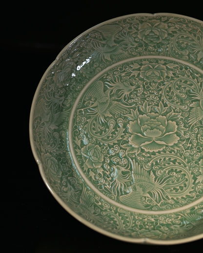 Northern Song carved celadon dish showing deep three-dimensional phoenix relief under olive glaze