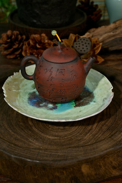 Artisanal soda-fired coaster plate displaying vibrant cosmic blue and brown flame marks
