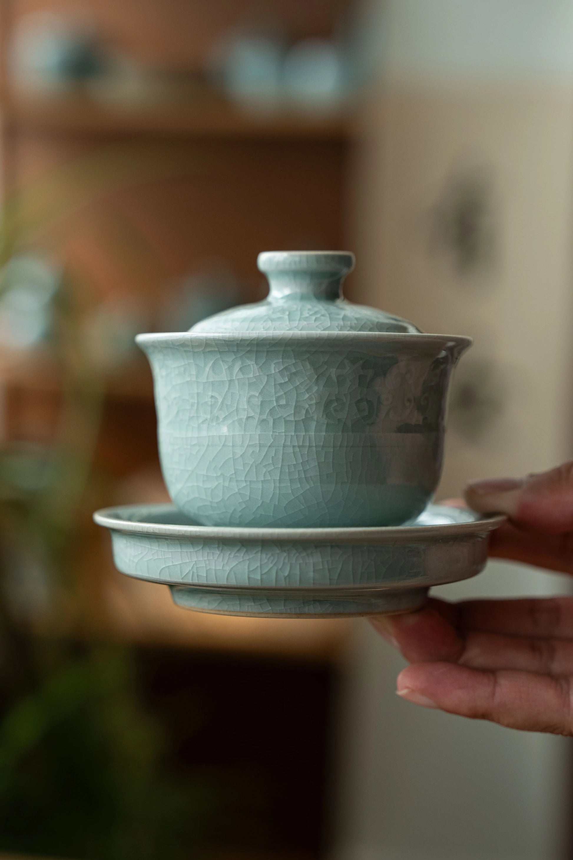 A hand holding the main teapot to demonstrate its compact size and comfortable grip for travel.