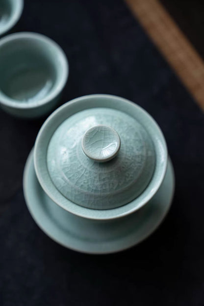 Detailed view of the main teapot or gaiwan featuring relief patterns and a smooth porcelain lid.