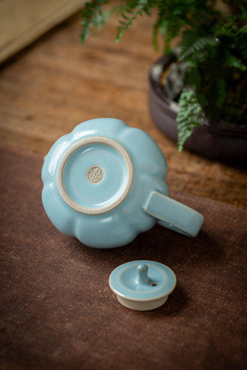 Ru kiln celestial blue pumpkin teapot with rounded lid and finial against dark background