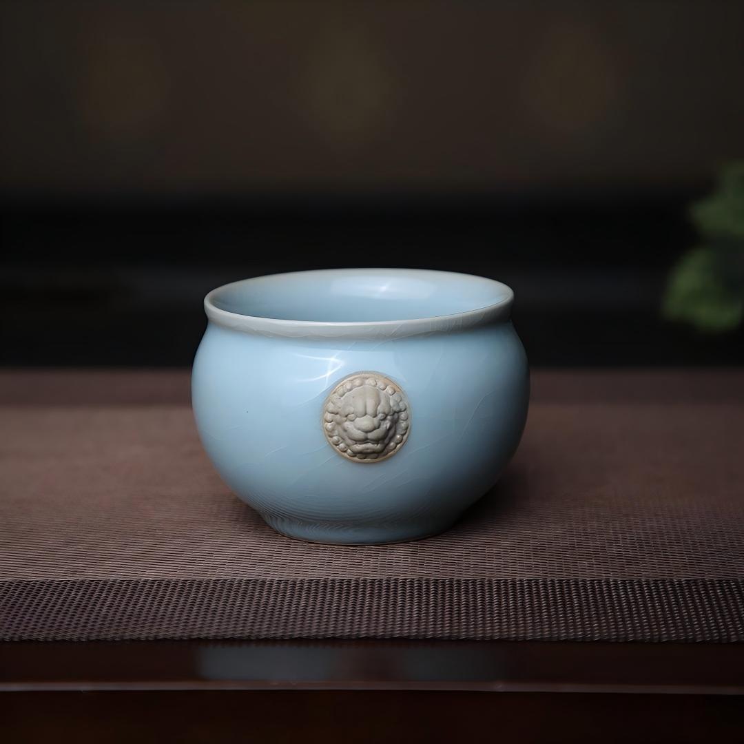 Hand-pinched tiger heads protruding from exterior wall of ceramic tea cup for visual interest and grip reference