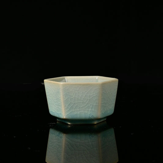 Ru Ware sky-blue glazed hexagonal master teacup resting on reflective dark surface