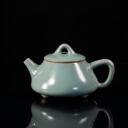Ru Ware sky-blue glazed three-legged Shipiao teapot resting on rustic brown woven mat