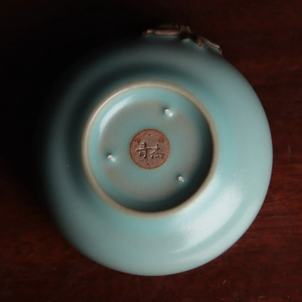 Unglazed dark clay biscuit dragon-lion motif applied on smooth glazed pottery.