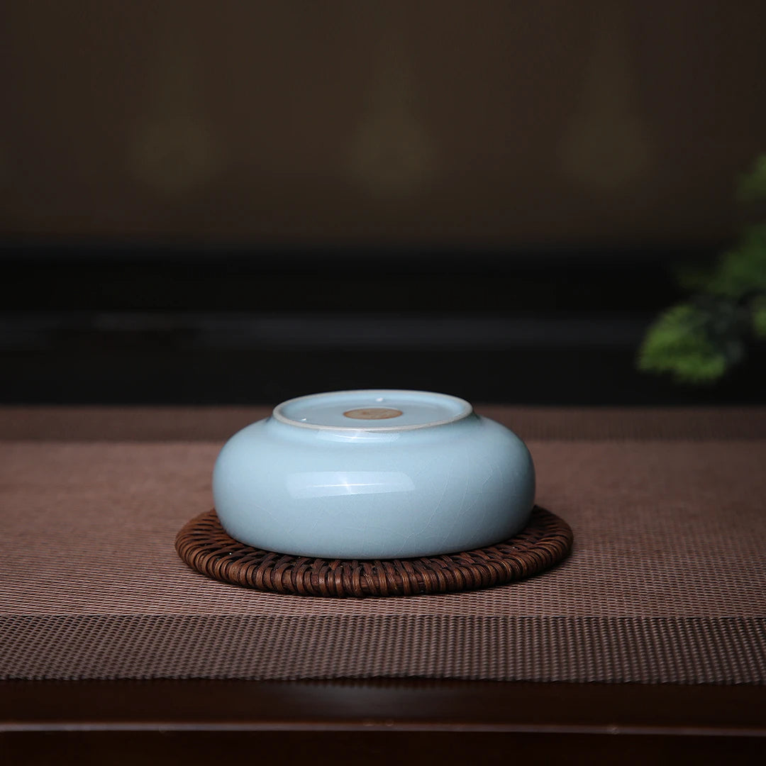 Ru Ware sky blue Pu'er teacup filled with dark amber tea liquor during Gongfu tea ritual