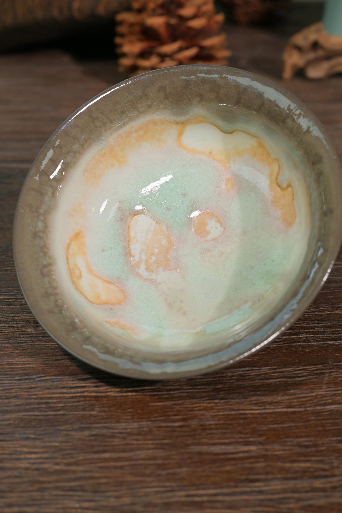 Chashao wood-fired gaiwan displaying milky white glaze with toasted bronze ash markings and moss green runs