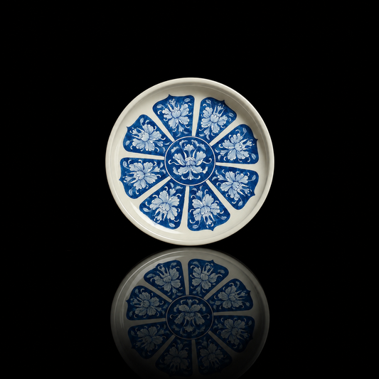 Top-down view of an antique-style blue-and-white tea tray with radiating peony patterns.