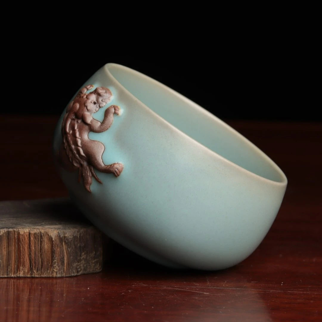 Close-up of a hand-sculpted mythical beast Pixiu on a sky-blue celadon tea cup.
