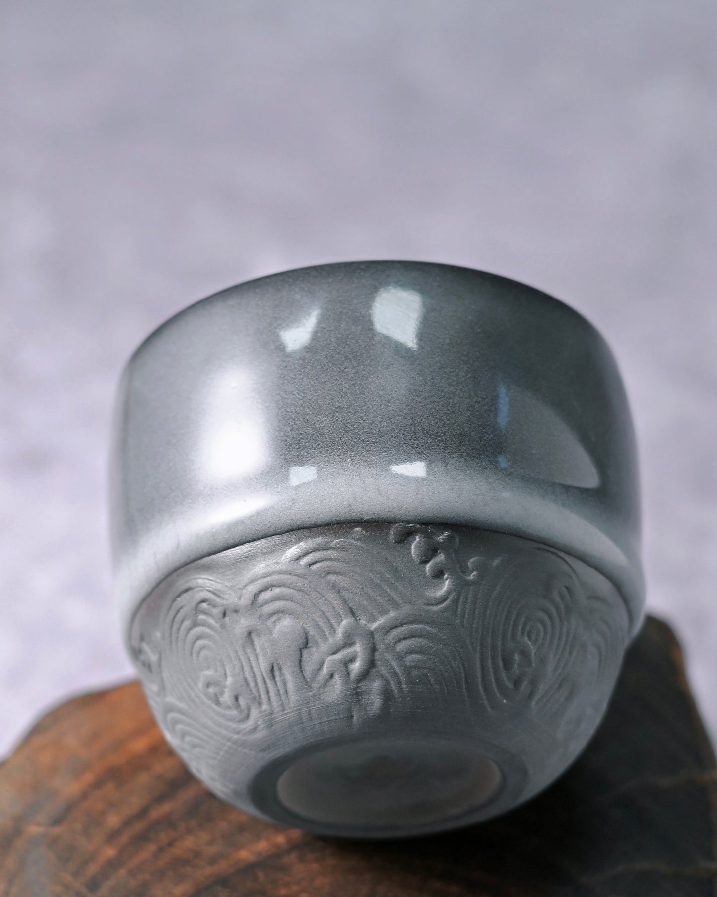 Thick celadon glaze surface teacup showing iron-blue coloration with glossy finish and subtle flow marks