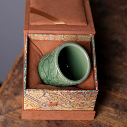 Gongfu tea setup featuring Longquan Celadon Taotie mask embossed teacup on rustic wood table