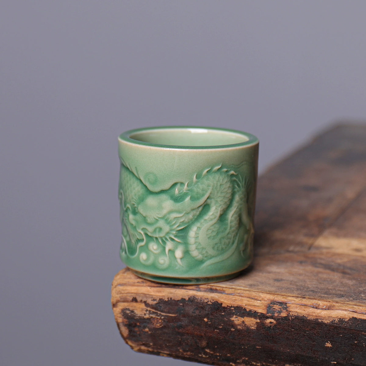 Gongfu tea setup featuring Longquan Celadon dragon embossed teacup on rustic wood table