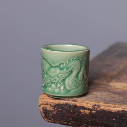 Gongfu tea setup featuring Longquan Celadon dragon embossed teacup on rustic wood table