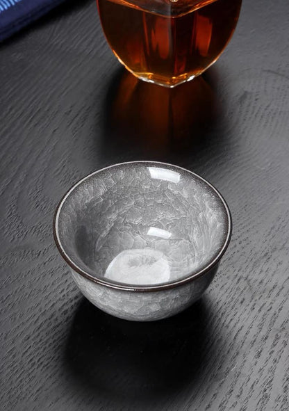 Traditional Chinese press-hand tea cup in Longquan celadon, featuring ice crackle patterning and weighted base for stability