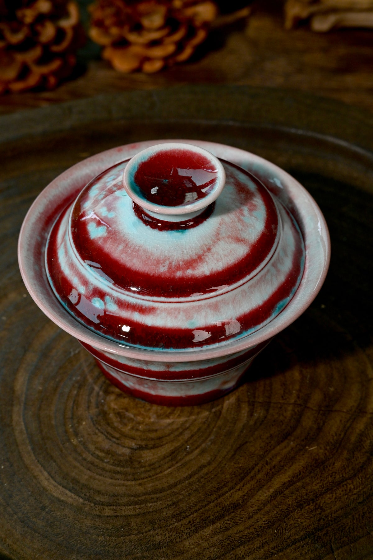 Top-down view of wood-fired bamboo Gaiwan lid finial coated in glowing flame-red glaze
