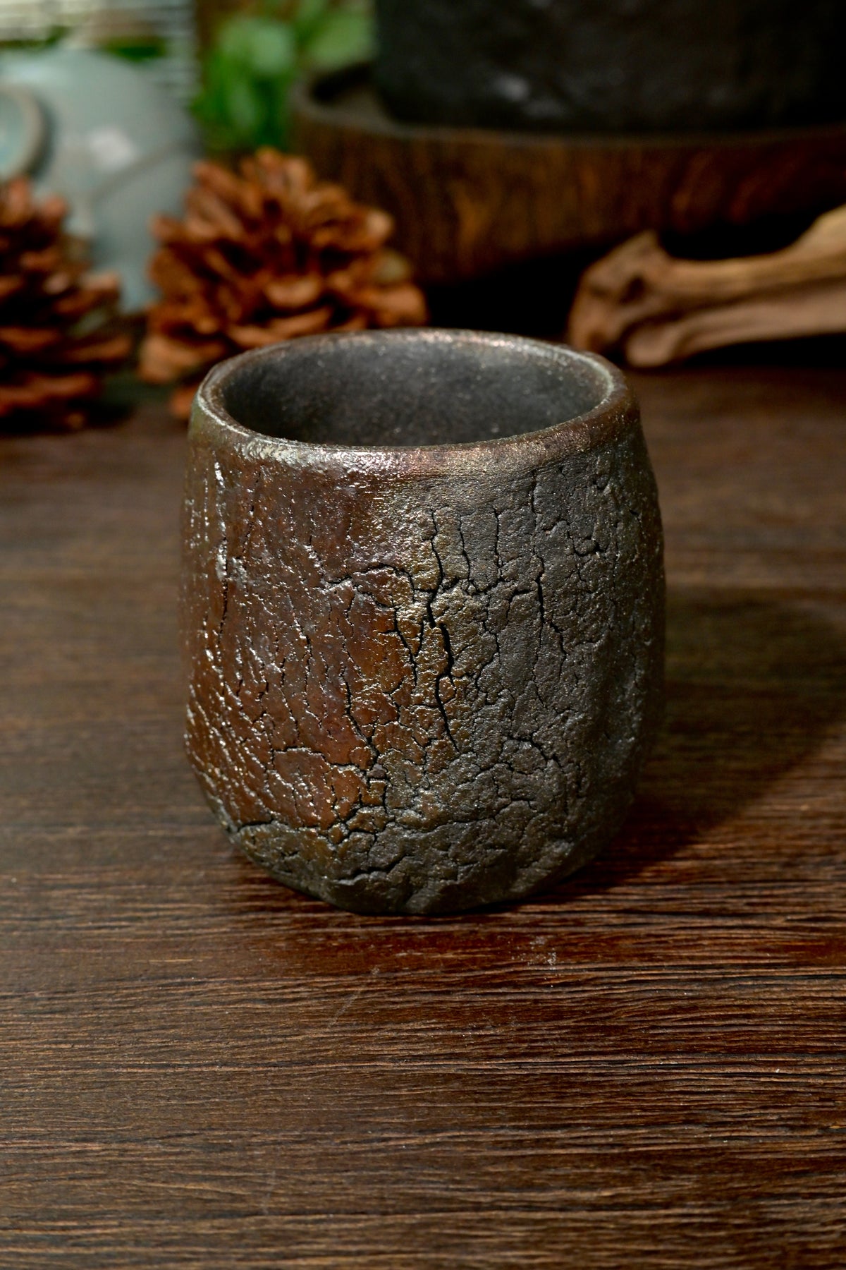 Handmade 1-of-1 unglazed wood-fired master cup resting on rustic dark timber tea table
