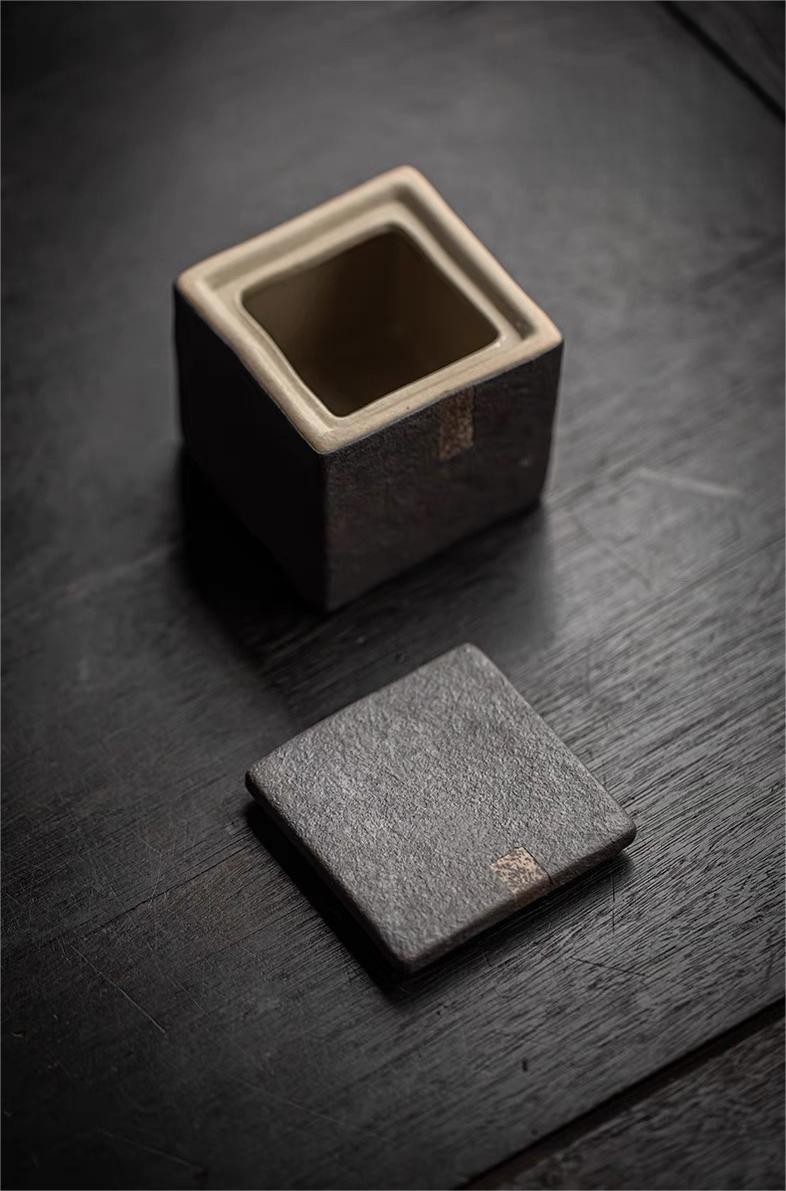 Natural unglazed tea caddy with rough tactile texture and minimalist square silhouette