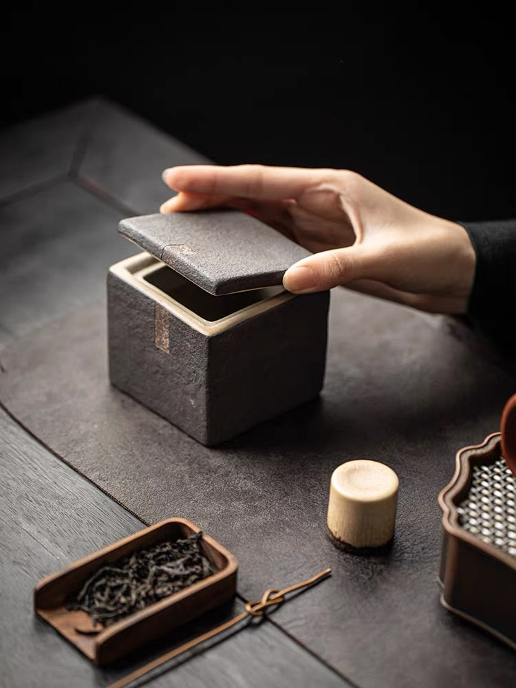 Unglazed wabi-sabi square tea caddy in raw clay with rough texture and natural ash markings
